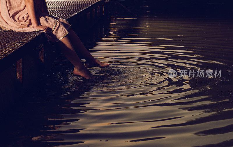 码头上一个双腿浸在水里的陌生女人。