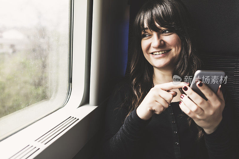 年轻女子在火车上使用手机，旅行