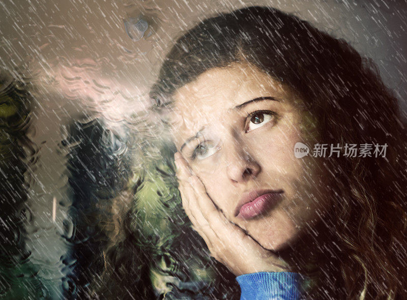 悲伤的年轻女子透过被雨淋湿的窗户