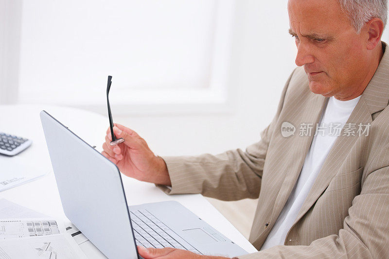 一个微笑的高级商务人士使用笔记本电脑的侧视图