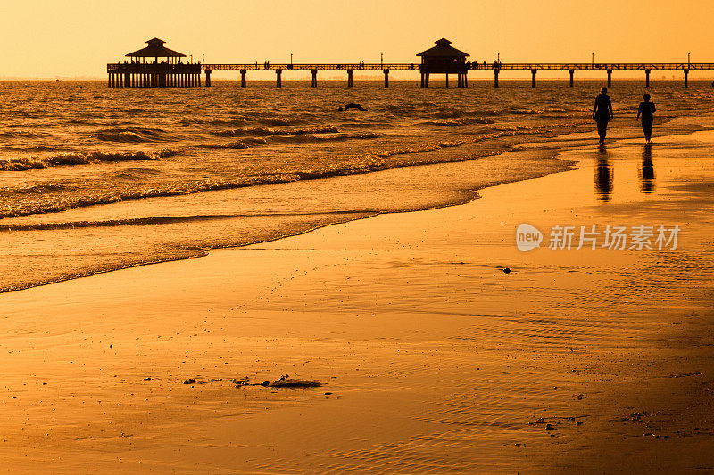日落时分，人们在海滩上散步