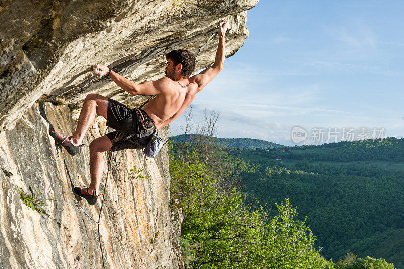 肌肉发达的男性攀岩者正在攀爬一个困难的悬垂物