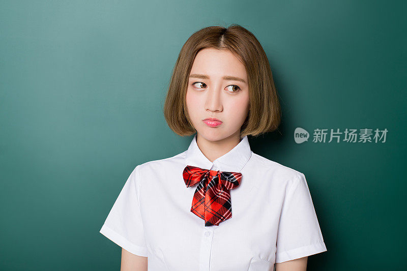 十几岁的中国女孩站在空白黑板前的肖像