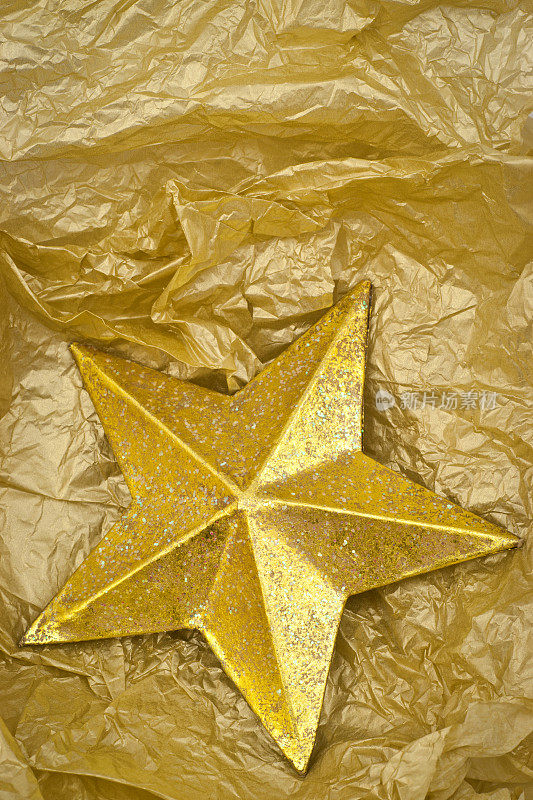 金色闪闪的圣诞星星装饰在金色的纸背景上