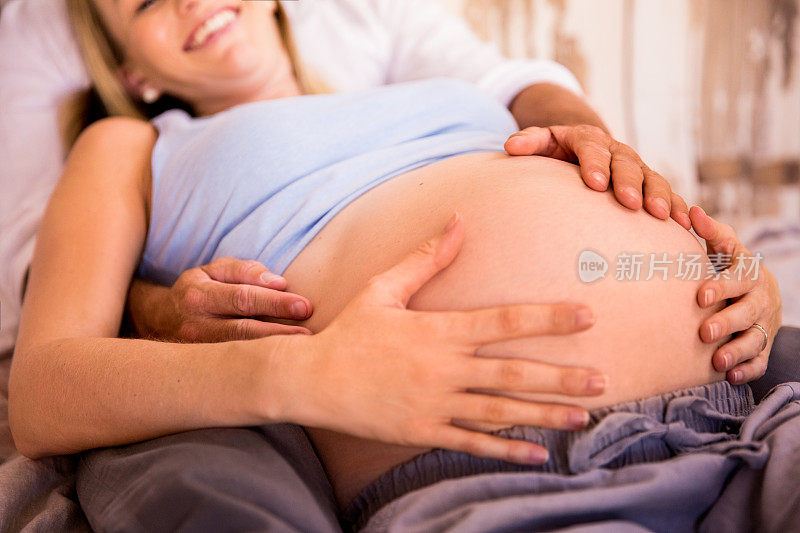 一对夫妻躺在床上抚摸妻子怀孕的肚子
