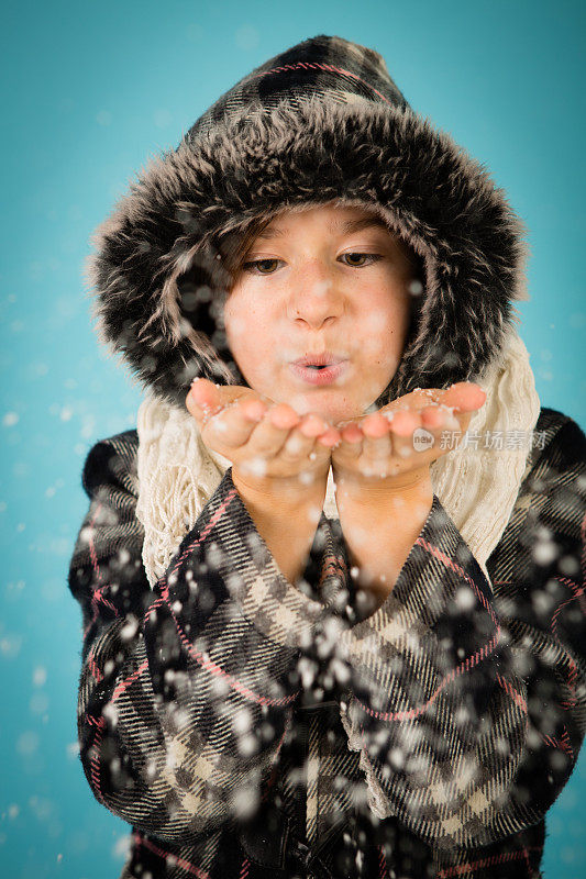 穿着暖和的小女孩吹一把雪