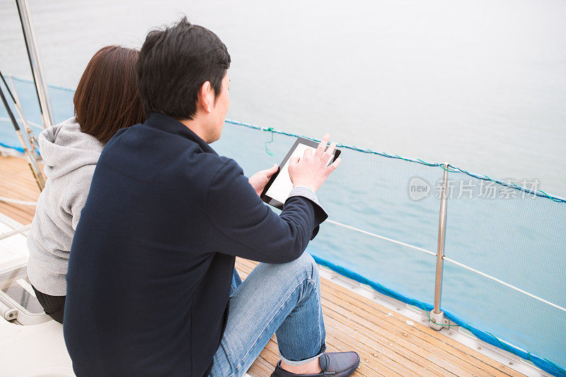 一对夫妇在豪华游艇上看数码平板电脑