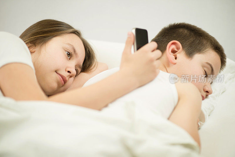 孩子们在床上玩智能手机