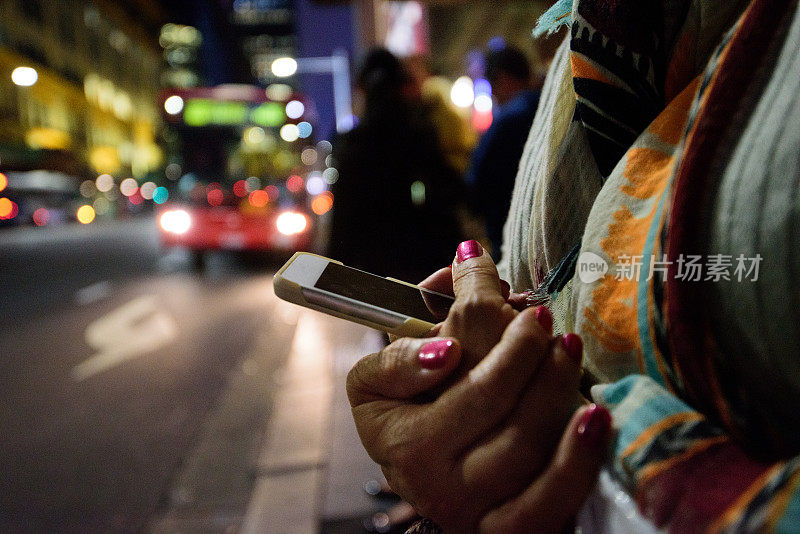 女人在等夜车，手里拿着手机