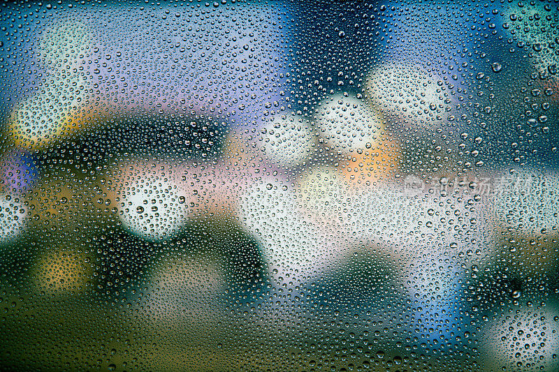 夜晚的城市灯光从一个下雨的窗户