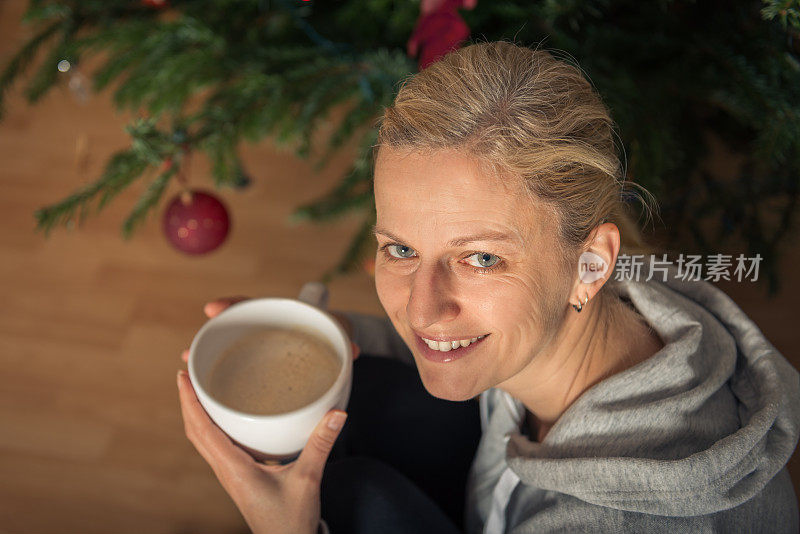 拿着杯子的女人站在圣诞树前