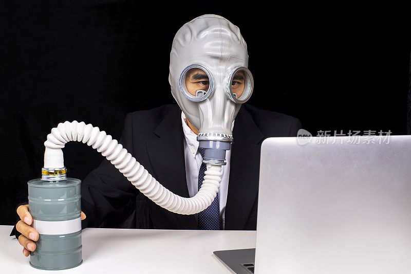 办公室职员戴着防毒面具，用笔记本电脑工作