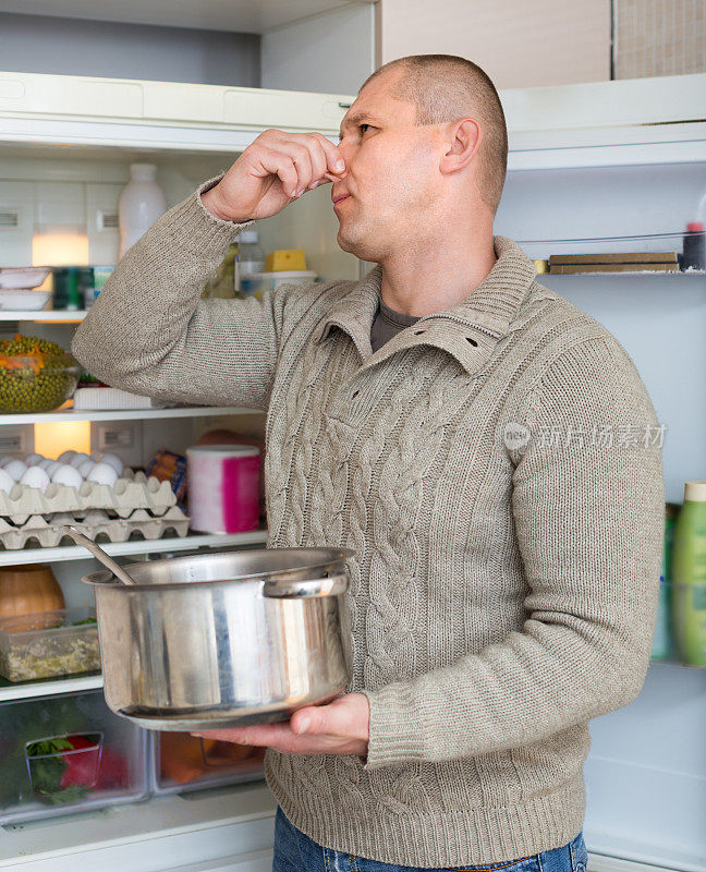 一个男人拿着不干净的食物靠近冰箱