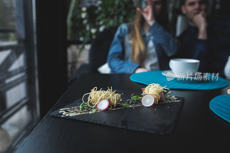 黑盘酱面虎虾。亚洲食品的概念。人们的背景在餐馆的地方与木桌。