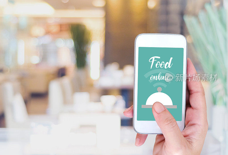 智能手机上的食物在线设备屏幕上模糊餐厅背景，食物在线，送餐概念