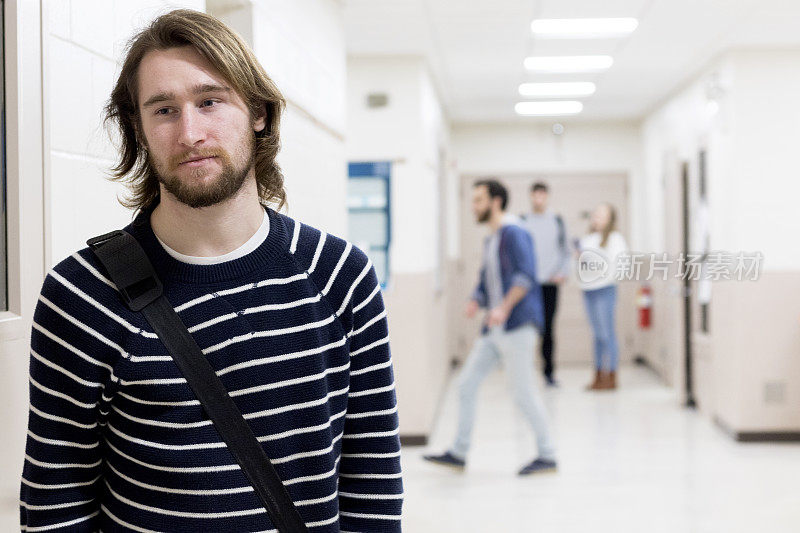 一个悲伤而分心的年轻大学生走在繁忙的走廊上