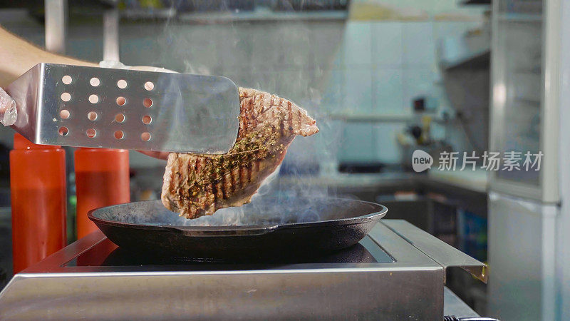 厨师的柔和焦点出现在烤肉架上的一块牛排上