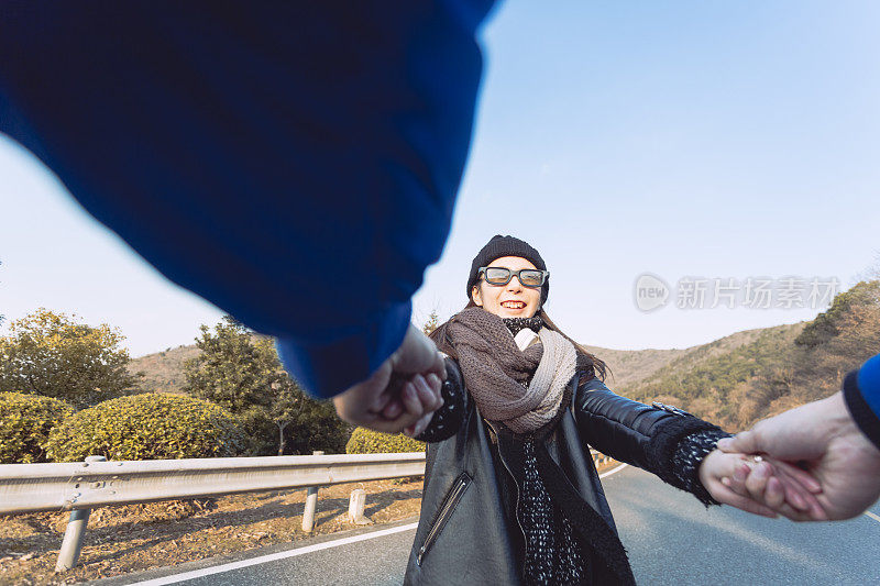 幸福的女朋友牵着男朋友的手在山路上