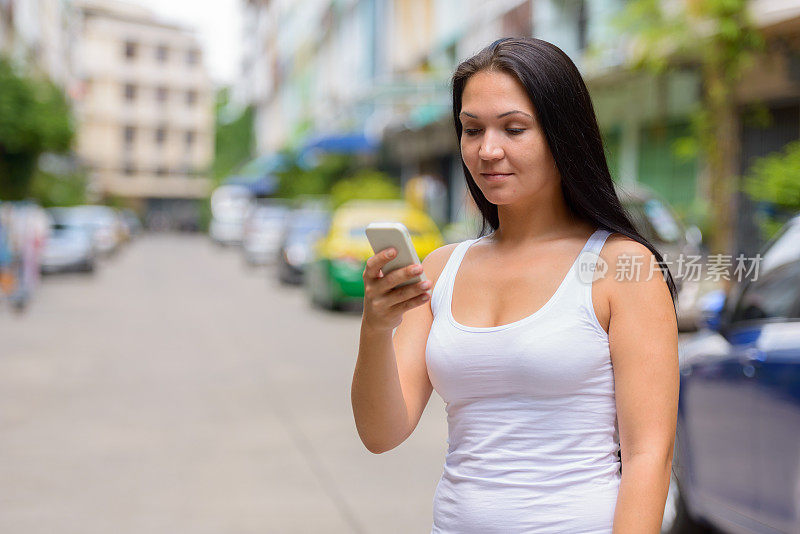 年轻的俄罗斯女游客在曼谷街头使用手机