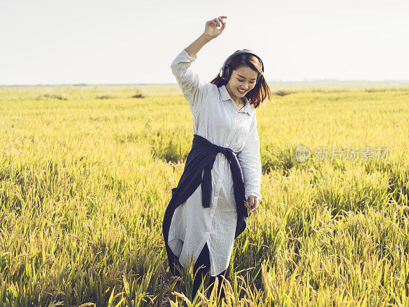 年轻女孩戴着耳机在野外跳舞