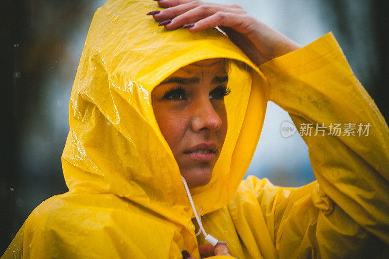 愁眉苦脸的女人穿着黄色的雨衣在下雨