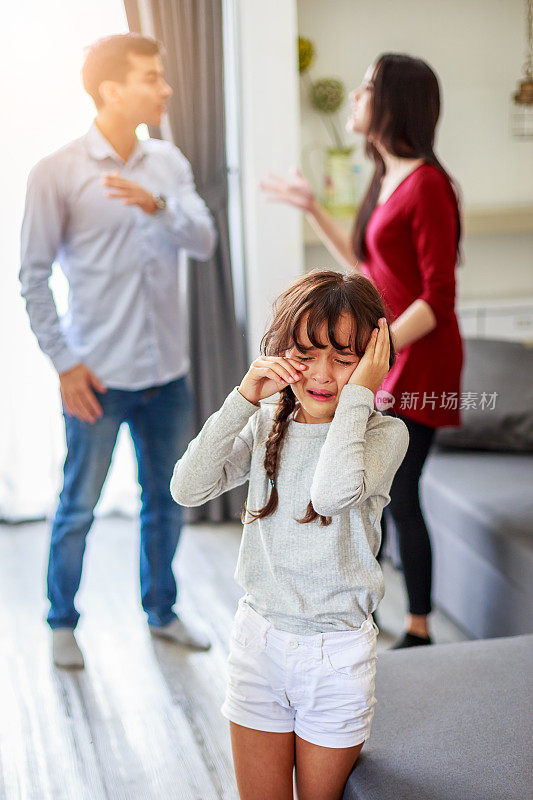 哭闹的女孩和吵架的父母在后面，悲伤的女孩而父母在客厅争吵