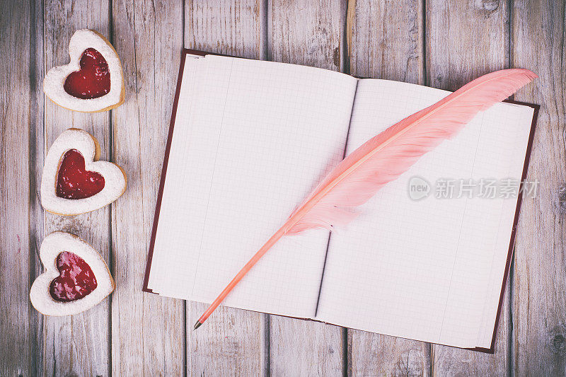 心形的饼干和空笔记本放在质朴的白色木桌上。