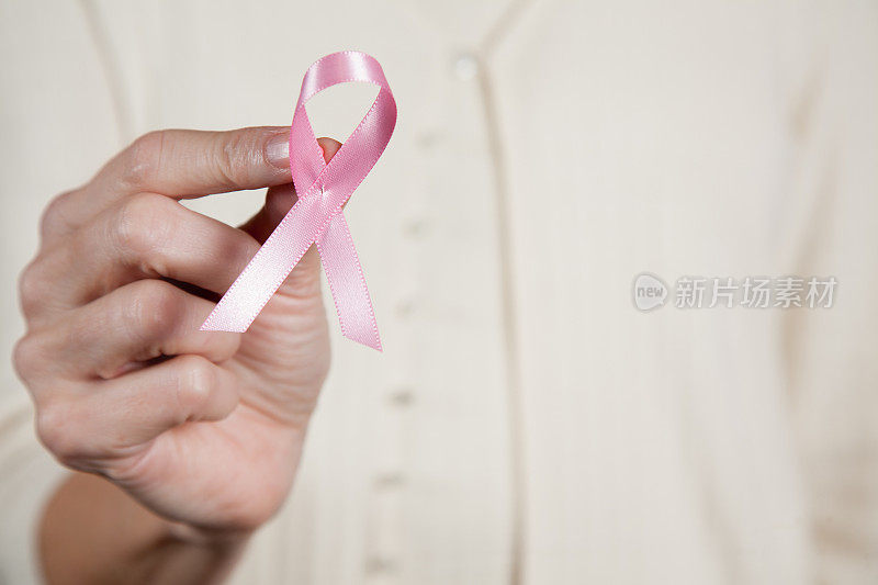 一个面目全非的人拿着乳腺癌丝带