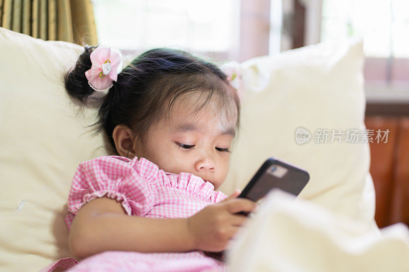 亚洲女婴在床上看智能手机