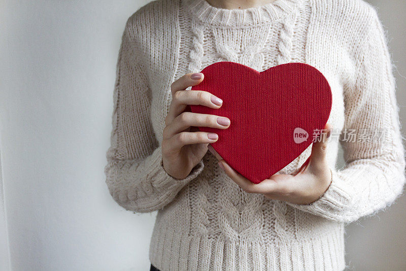 年轻女子拿着心形的红色礼盒-情人节