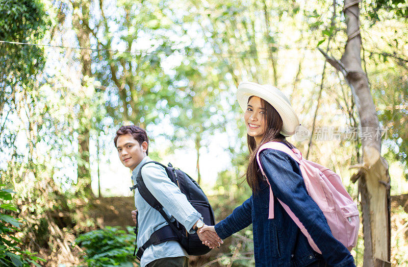 一对年轻夫妇手牵着手一起在公园里散步