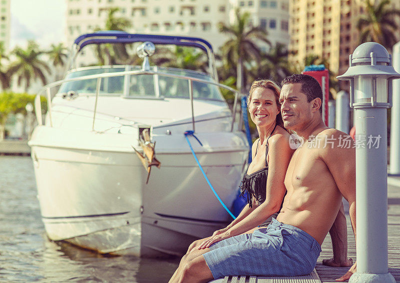 一对穿着泳衣的漂亮的成年夫妇在海边的一个码头上，奢华而田园般的位置