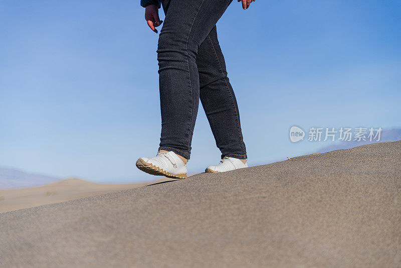 在加州死亡谷梅斯奎特平原的沙丘上徒步旅行的妇女。注意腿，特写。