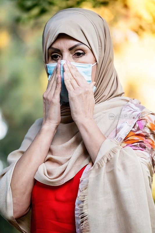 严肃的中东穆斯林妇女正在调整她的防护面罩
