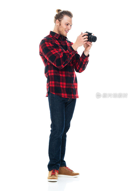 白人男性摄影师站在白色背景前，穿着衬衫，拿着相机