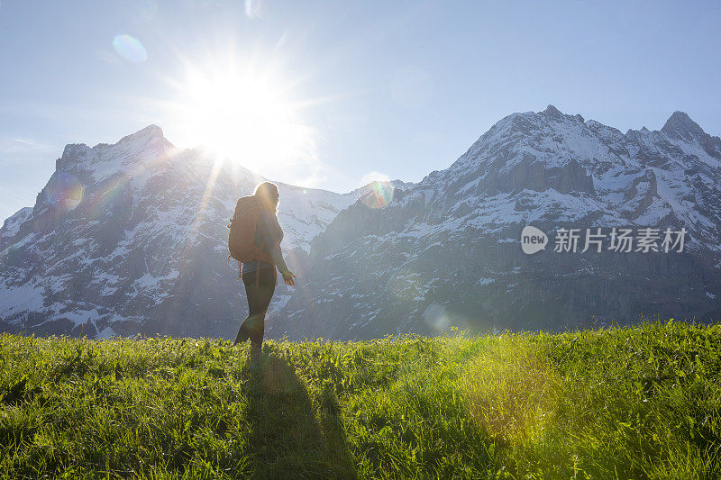 女性徒步者攀登草甸斜坡，在山上