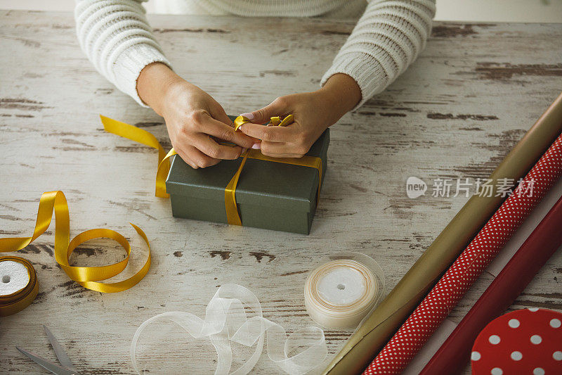 桌子上有一卷装饰包装纸和女性的手装饰礼品