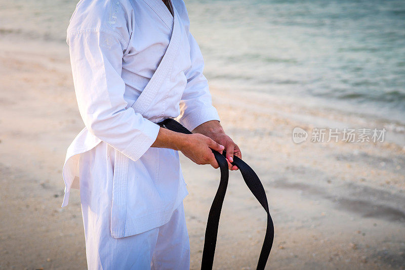 一名男子在海边的和服上调整他的空手道黑带