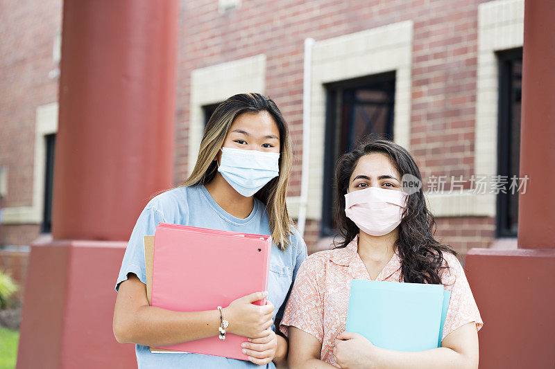 两个年轻的成年女性带着防护口罩回到学校