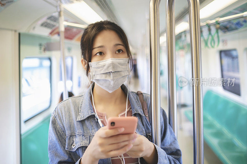 亚洲女性在乘坐地铁或火车时，会戴口罩、使用智能手机和耳机，并保持社交距离