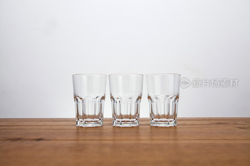 三个空的水杯排成一行放在一张木桌上，用复印空间直接观察