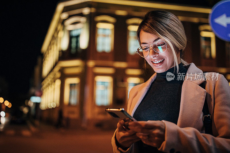 一个年轻女子站在城市的街道上使用手机