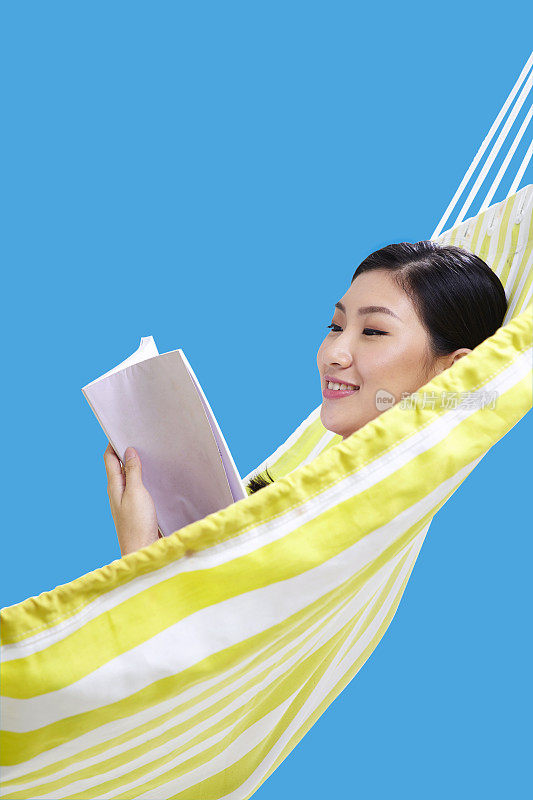 一个中国妇女躺在吊床上看书
