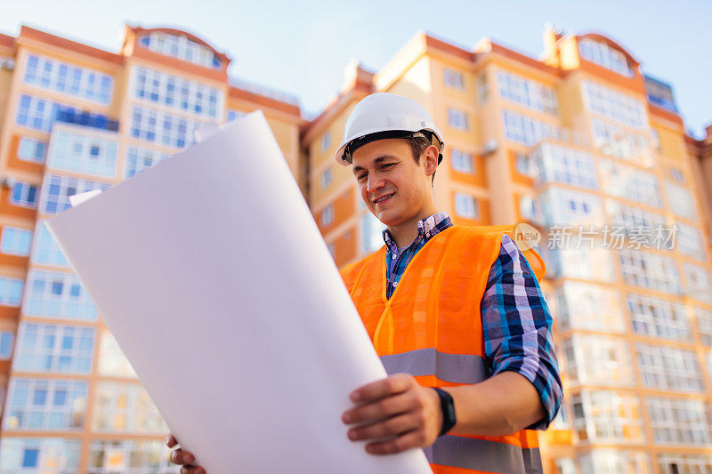 工程师、建筑工人穿着印有图纸的安全背心在施工现场