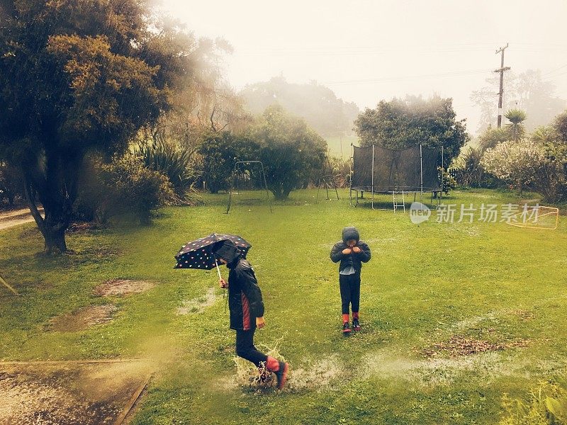 孩子们在花园里的雨中玩耍