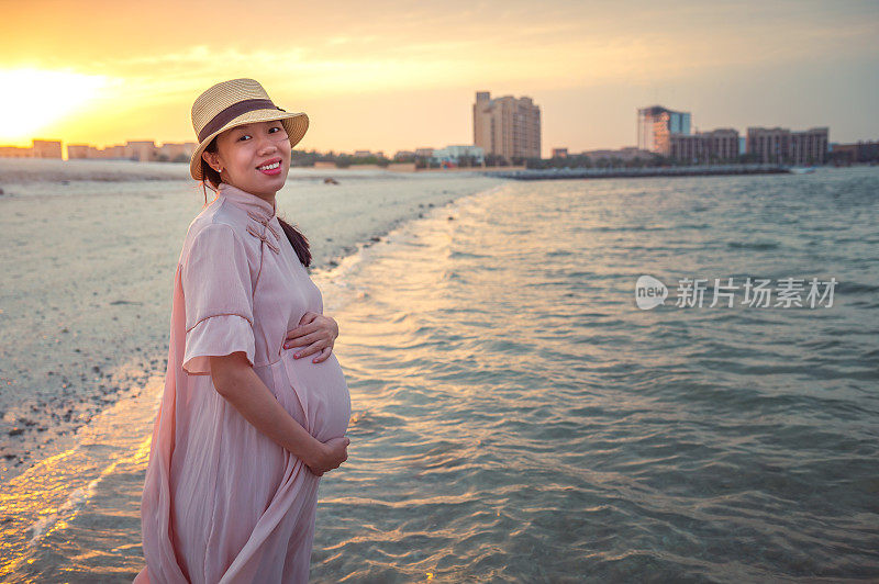 日落时分，一名孕妇在海边的海滩上