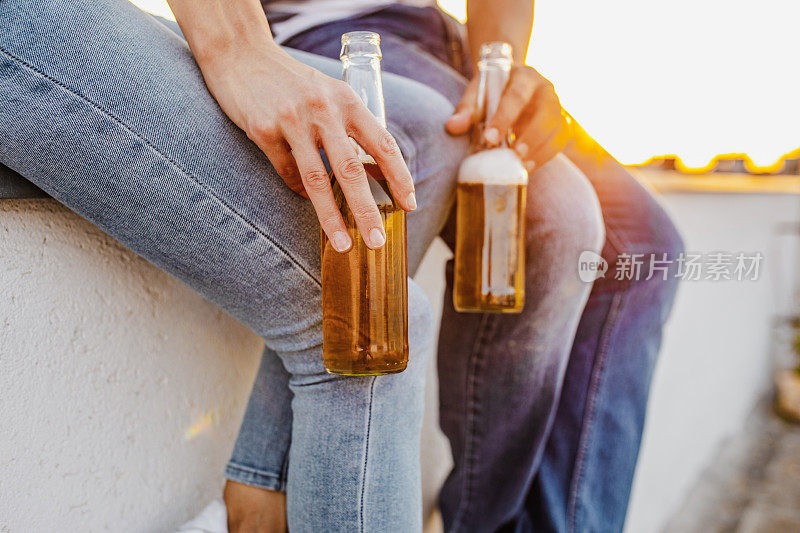 女性和男性手握啤酒瓶的特写照片