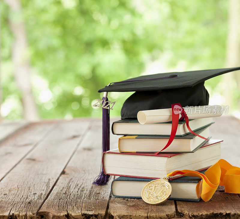 毕业2021帽，文凭和致告别辞的学生奖章在一个木头的背景