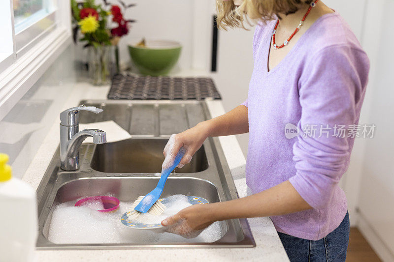 十几岁的女孩在厨房水槽里洗盘子