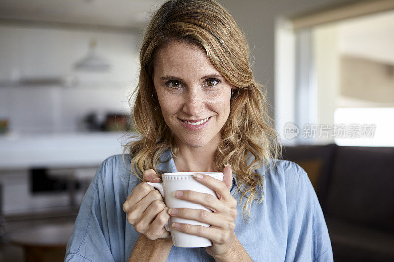 中年妇女坐在家里双手捧着一杯咖啡的肖像